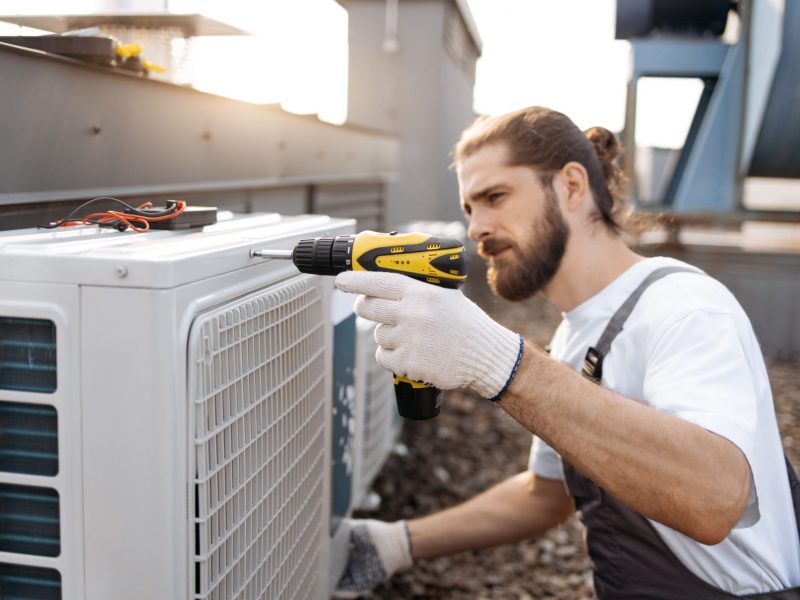 male-worker-repairing-conditioner-while-using-dril-2024-12-10-04-06-45-utc